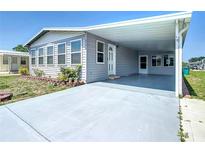 Charming single-story home with a covered carport and well-maintained landscaping, painted in neutral gray tones at 6739 Kensington Ne Dr, Winter Haven, FL 33881
