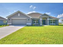 Gray house with a two-car garage and a landscaped lawn at 4081 Tullamore Ln, Auburndale, FL 33823