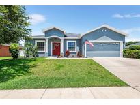 Charming single-story home with well-maintained lawn, classic columns, and a bright red front door at 192 Viola Dr, Auburndale, FL 33823