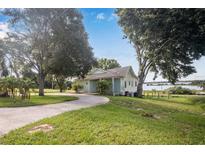 House exterior showcasing a light-blue home with mature trees and a long driveway at 420 W Gates Ave, Lake Hamilton, FL 33851