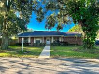 Charming brick home with well-manicured lawn, sidewalk and mature trees creating a welcoming curb appeal at 426 Lanier Ln, Winter Haven, FL 33884