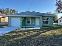 Newly constructed teal home with a two-car garage and a well-manicured lawn at 833 3Rd Ave, Waverly, FL 33877