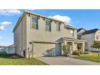 Two-story house with light beige siding, two-car garage, and a manicured lawn at 935 Waterville Dr, Auburndale, FL 33823