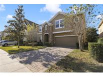 Two-story home with a two-car garage, stone accents, paved driveway and manicured front lawn at 137 Drayton Ave, Davenport, FL 33837