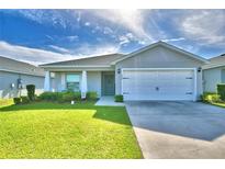 Charming single-story home featuring a well-manicured lawn, a two-car garage, and covered entry at 566 Valentina Ln, Auburndale, FL 33823