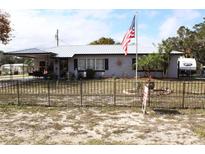 Charming single-story home with a metal roof, covered porch, fenced yard, and American flag waving out front at 5031 Timberlane Rd, Lake Wales, FL 33898
