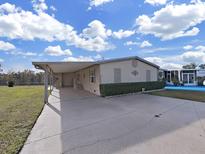 Tan mobile home with carport, landscaping, and paved driveway at 1750 Fox Hill Dr, Lakeland, FL 33810