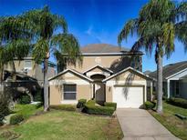 Two-story house with tan exterior, palm trees, and a two-car garage at 2877 Kokomo Loop, Haines City, FL 33844