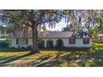 Single-story home with a large tree and manicured lawn at 5090 Misty Lake Dr, Mulberry, FL 33860