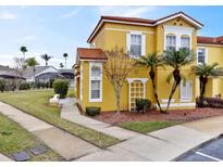 Two-story yellow house with a red tile roof, landscaping, and a walkway at 938 Park Terrace Cir, Kissimmee, FL 34746