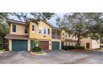 Exterior view of a yellow condo building with green and brown garages at 12220 Wild Iris Way # 110, Orlando, FL 32837
