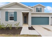 Two-story house with gray siding, teal garage door, and landscaping at 245 Hillcrest Dr, Dundee, FL 33838