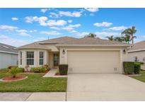 Tan one-story house with a two-car garage and well-manicured lawn at 340 Lake Suzanne Dr, Lake Wales, FL 33859