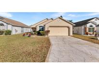 Tan one-story house with a two-car garage and well-maintained lawn at 426 Allison Ave, Davenport, FL 33897