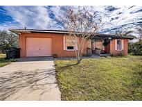 Orange house with fire damage, boarded windows, and a pink garage door at 517 Cipres Cir, Winter Haven, FL 33880