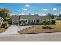 Tan house with green roof, landscaping, and driveway at 615 E Haines Blvd, Lake Alfred, FL 33850