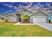 Gray house with two-car garage, palm trees, and well-maintained lawn at 1932 Southern Dunes Blvd, Haines City, FL 33844