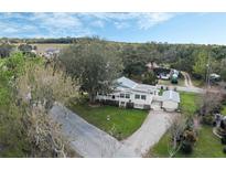 Stunning aerial view of a charming home with lush greenery, spacious yard and gravel driveway at 922 S Lake Reedy Blvd, Frostproof, FL 33843