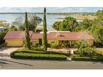 Lakefront home featuring a red tile roof and lush landscaping, offering serene views and curb appeal at 1121 Sunset Dr, Lake Wales, FL 33853