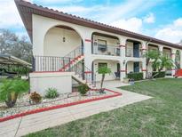 Charming two-story condo building featuring a red tile roof, lush landscaping, and private balconies at 2002 Granada Ct # 1, Lake Wales, FL 33898