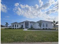 Beautiful one-story home with a well-manicured lawn and lush tropical landscaping at 4593 Emerald Palms Dr, Winter Haven, FL 33884