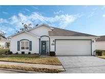 White house with teal accents, two-car garage, and landscaped lawn at 524 Lake Suzanne Dr, Lake Wales, FL 33859