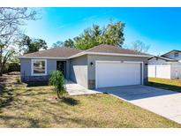 Newly constructed home with gray siding, a white garage door and a well-manicured lawn at 834 Avenue I Ne, Winter Haven, FL 33881