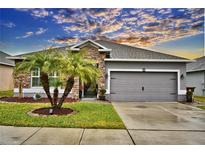 Single-story home with gray siding, stone accents, and a two-car garage at 918 Revere Ave, Haines City, FL 33844