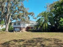 Two-story home featuring brick and white siding, complemented by lush landscaping and mature trees at 148 Lake Otis Rd, Winter Haven, FL 33884