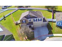 Two-story tan home with blue shutters, neutral colored siding, a well-manicured lawn, and an attached two-car garage at 1510 Shorewood Dr, Auburndale, FL 33823