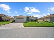 Charming single-story home with a well-manicured lawn and a brick driveway at 1017 Sawgrass Dr, Winter Haven, FL 33884