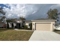 Attractive single-story home featuring a two-car garage, neutral stucco, well-maintained lawn, and simple landscaping at 1205 Lake Loop Rd, Winter Haven, FL 33880