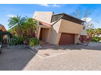 Unique home exterior with a two-car garage, brick driveway, stucco walls and tropical landscaping at 15 Casarena Ct, Winter Haven, FL 33881