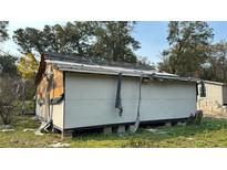 Damaged exterior of unfinished home with partial siding and roof repairs evident in rural setting at 1928 Old Apopka Rd, Apopka, FL 32703