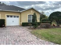 Charming single-Gathering home features an attached garage, brick driveway, and manicured landscaping at 2673 Rutledge Ct, Winter Haven, FL 33884