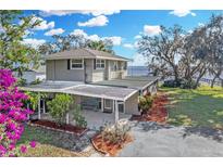 Inviting waterfront home featuring a covered patio, lush landscaping, and serene water views at 3943 Chambers St, Lake Wales, FL 33898
