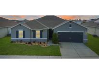 Charming single-story home featuring a well-manicured lawn and a two-car garage at 5767 Lakeside Landings Blvd, Winter Haven, FL 33881