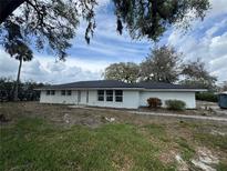 Charming single-story home with a modern white exterior and new roof, nestled under mature trees at 625 W Pipkin Rd, Lakeland, FL 33813