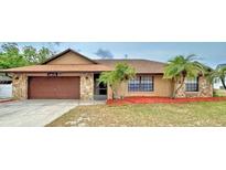 Charming single-story home with a stone facade, mature landscaping, and a two-car garage at 1412 Covington Ct, Lake Wales, FL 33853