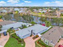 Stunning aerial view of a home with brick driveway, lush landscaping, and waterfront views within a quiet neighborhood at 3416 Grenville Dr, Winter Haven, FL 33884