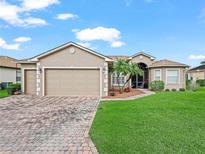 Charming single Gathering home boasting a well-manicured lawn, brick-paved driveway, and attached garage at 4073 Sable Loop Dr, Lake Wales, FL 33859