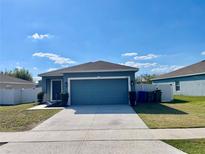 Inviting single-story home with a two-car garage, well-manicured lawn, and beautiful blue siding at 663 Lucerne Blvd, Winter Haven, FL 33881