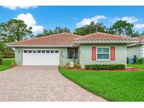 Charming single-story home features a red tile roof, lush landscaping, and a brick-paved driveway leading to a two-car garage at 762 Canberra Rd, Winter Haven, FL 33884