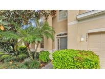 Charming home entrance with a beautiful gray door, complemented by lush landscaping, creating a welcoming ambiance at 7759 Basnett Cir, Kissimmee, FL 34747