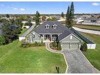 Stunning aerial view of home featuring a manicured lawn, brick driveway, mature trees, and a fenced-in backyard at 819 Hart Lake St, Winter Haven, FL 33884