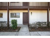 Inviting condo entrance with a wooden door, outdoor lighting, and tidy landscaping at 1104 Country Club Dr # A-4, Lake Wales, FL 33898