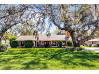 Charming single-story home with a brick chimney, well-manicured landscaping, and mature trees in the front yard at 3614 Twisted Oak Ct, Lake Wales, FL 33898