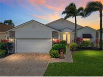 Charming home featuring a brick driveway, well-manicured lawn, and lush landscaping with tropical palm trees at 4115 Muirfield Loop, Lake Wales, FL 33859