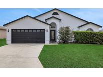 Charming home featuring a well-manicured lawn, dark garage door, and inviting front entrance at 412 Savanna Pointe St, Winter Haven, FL 33884