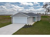 Charming single-story home with a two-car garage, freshly landscaped garden, and light blue front door at 42 Mountain Dr, Babson Park, FL 33827